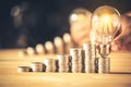 Hand holding a light bulb with coins stack. Creative ideas for saving money concept. Royalty Free Stock Photo