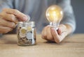 Hand holding a light bulb with coins stack. Creative ideas for saving money concept. Royalty Free Stock Photo