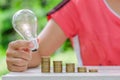 Light bulb with Coins stack on wooden table in the morning. Energy and Money saving , accounting and financial concept Royalty Free Stock Photo