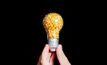 Hand holding a light bulb full of popcorn kernels
