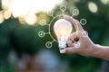 Hand holding light bulb with icons energy sources for renewable, love the world concept Royalty Free Stock Photo