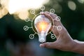 Hand holding light bulb with icons energy sources for renewable, love the world concept Royalty Free Stock Photo