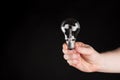 Hand Holding a light bulb, isolated on gradient black background Royalty Free Stock Photo