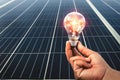 hand holding light bulb with solar panel background Royalty Free Stock Photo