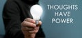 Hand holding light bulb with text Thoughts Have Power.