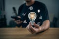 Hand holding light bulb with virtual AI brain inside and glowing technology icons for innovation, creative idea, machine learning Royalty Free Stock Photo