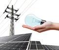 Hand holding lightbulb. In the background solar panel and high voltage tower. Royalty Free Stock Photo