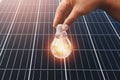 hand holding lightbulb with solar panel background. clean energy in nature concept Royalty Free Stock Photo