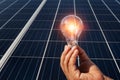 hand holding lightbulb on solar panel concept clean energy in nature Royalty Free Stock Photo