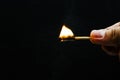 Hand holding lighted match with black background Royalty Free Stock Photo