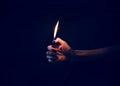 Hand holding lit lighter in the dark Royalty Free Stock Photo