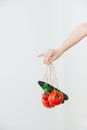 Hand holding little string bag with tomatoes and cucumbers Royalty Free Stock Photo