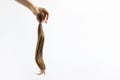 Hand holding long blond hair donation tightened with ribbon ponio for cancer patient on white background. Natural material for Royalty Free Stock Photo