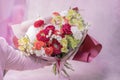 A hand is holding a lush beautiful bouquet of red, orange, yellow, white cute delicate flowers of different sizes and colors Royalty Free Stock Photo