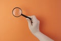 Hand holding a magnifier against color background Royalty Free Stock Photo