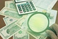 hand holding magnifier with coins and dollar banknote,concept bu Royalty Free Stock Photo