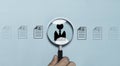 Hand holding magnifier glass with businessman icon and resume for human resource and development recruits and select employees who