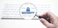 Hand holding magnifying glass on computer keyboard. Security Royalty Free Stock Photo