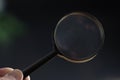 hand holding magnifying glass in dark room. concept of uncovering mystery, detective investigation, solve secret