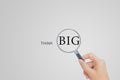 Hand holding magnifying glass and looking to THINK BIG wording text om gray background. Royalty Free Stock Photo