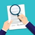 Hand holding magnifying glass over a contract