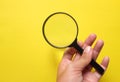hand holding Magnifying glass  on a yellow backgrou Royalty Free Stock Photo