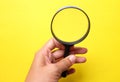 Hand holding Magnifying glass  on a yellow backgrou Royalty Free Stock Photo