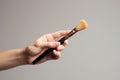 Hand holding makeup brush, cosmetic equipment in studio. Beauty concept, man\'s make up. AI generated Royalty Free Stock Photo