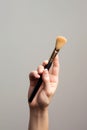 Hand holding makeup brush, cosmetic equipment in studio. Beauty concept, man\'s make up. AI generated Royalty Free Stock Photo