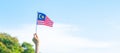 Hand holding Malaysia flag on blue sky background. September Malaysia national day and August Independence day Royalty Free Stock Photo