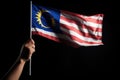 hand holding malaysia flag, isolated on black, political concept, Hand waving Malaysia flag also known as Jalur Gemilang in