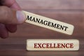 Hand holding management excellence text on wooden blocks. Management excellence and business concept Royalty Free Stock Photo