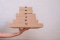 Hand holding many stacked carton pizza boxes of different sizes, restaurant delivery packging concept