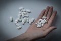 Hand holding many white prescription drugs, medicine tablets or vitamin pills in a pile - Concept of healthcare, opioids addiction Royalty Free Stock Photo