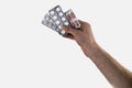 Hand holding medical drugs - full silver leaflet of white pills in common tablets shape, isolated on white background Royalty Free Stock Photo