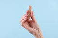 Hand holding medical plaster on blue background Royalty Free Stock Photo