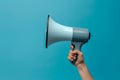 Hand holding megaphone isolated on blue background Royalty Free Stock Photo