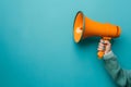 Hand holding megaphone isolated on blue background Royalty Free Stock Photo