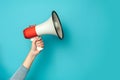 Hand holding megaphone isolated on blue background Royalty Free Stock Photo