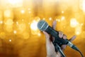 Hand holding microphone on stand with bokeh .