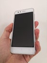 Hand holding a mid-range cheap white smartphone on white background