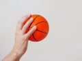 Hand holding mini basketball, copy space. Light background