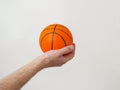 Hand holding mini basketball, copy space. Light background