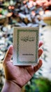 Hand holding a mini book written Al-Mathurat in Arabic word