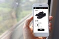 Hand holding mobile ecommerce website with black sneakers page i Royalty Free Stock Photo