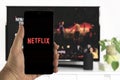 Hand holding a mobile with the Netflix app logo on it. Royalty Free Stock Photo