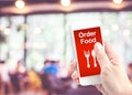 Hand holding mobile with Order food with blur restaurant background, Order food onine business concept Royalty Free Stock Photo