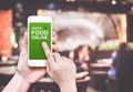 Hand holding mobile with Order food online with blur restaurant