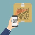 Hand holding mobile phone with app for scanning QR code on cardboard box