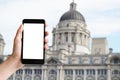 Hand holding mobile phone with blank screen and historic building at Liverpool Royalty Free Stock Photo